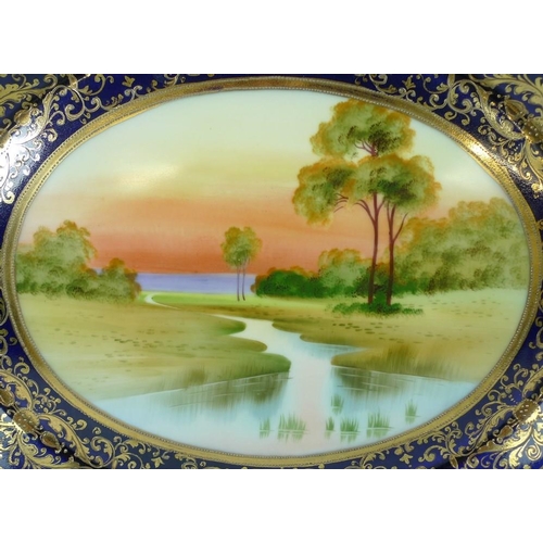 532 - A Japanese Noritake porcelain oval tray, 20th century, hand painted with a river landscape, 33 by 26... 