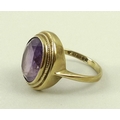 A 9ct gold and amethyst dress ring, the central oval cut amethyst of approximately 12 by 10mm within... 