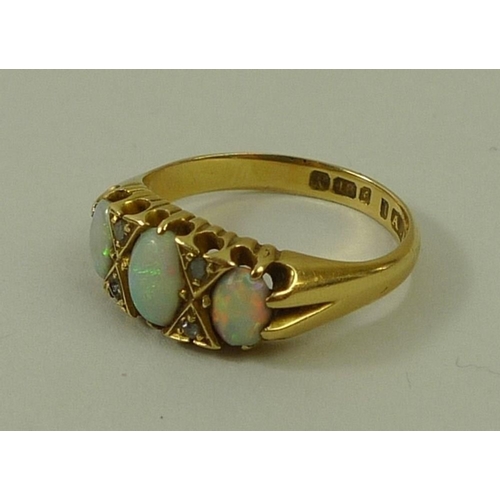 801 - An 18ct gold, opal and diamond ring, the three graduated oval cut opals divided by two pairs of chip... 