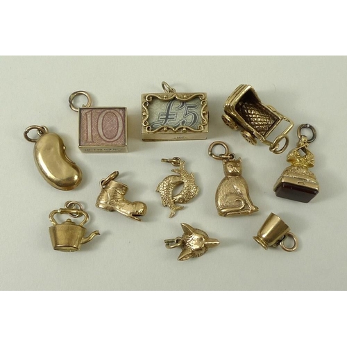 821 - A group of eleven gold charms, including a #5 note, an agate fob seal, cat shaped charm, kidney bean... 