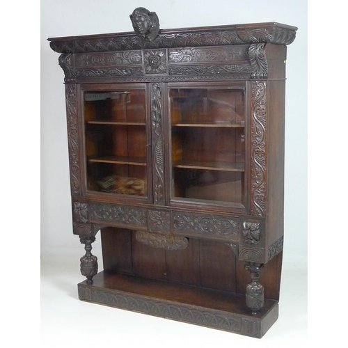 900 - A Victorian stained oak carved bookcase, with 17th century carved angel / cherub mask attached centr... 