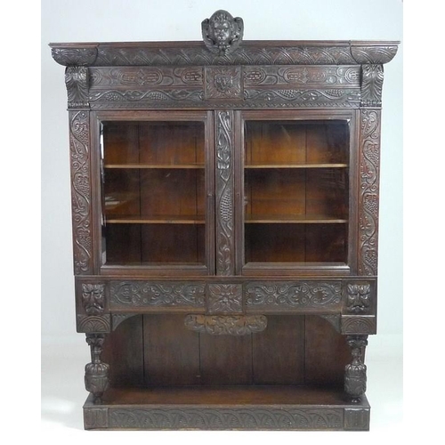 900 - A Victorian stained oak carved bookcase, with 17th century carved angel / cherub mask attached centr... 