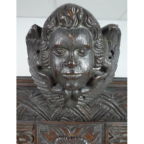 900 - A Victorian stained oak carved bookcase, with 17th century carved angel / cherub mask attached centr... 