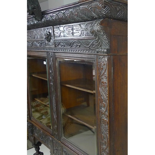 900 - A Victorian stained oak carved bookcase, with 17th century carved angel / cherub mask attached centr... 