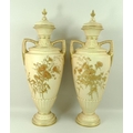 A pair of Royal Worcester blush ivory twin handled vases and covers, decorated with thistles in high... 