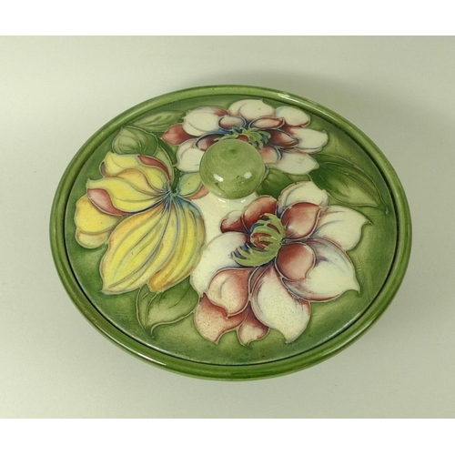 525 - A Moorcroft pottery dish and cover, in green ground decorated with peonies, 17 by 10cm.