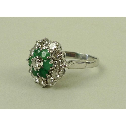 840 - An 18ct white gold, emerald and diamond dress ring, a central diamond surrounded by six emeralds in ... 