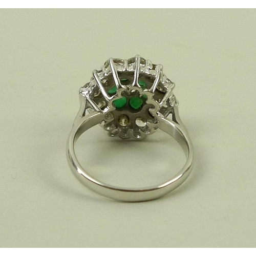 840 - An 18ct white gold, emerald and diamond dress ring, a central diamond surrounded by six emeralds in ... 