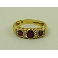 An 18ct gold three stone ruby and diamond dress ring, the central oval ruby flanked by two smaller r... 