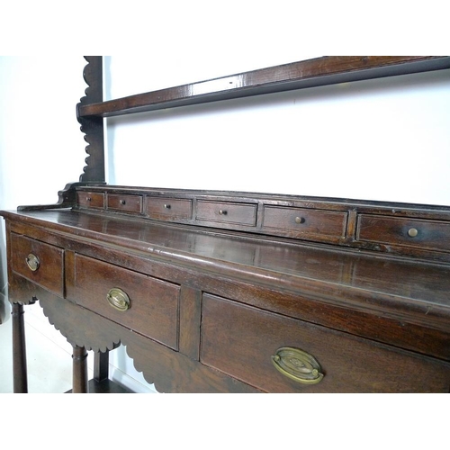 996 - An early Georgian oak dresser and rack of small proportions, with stepped cornice over a shaped frie... 