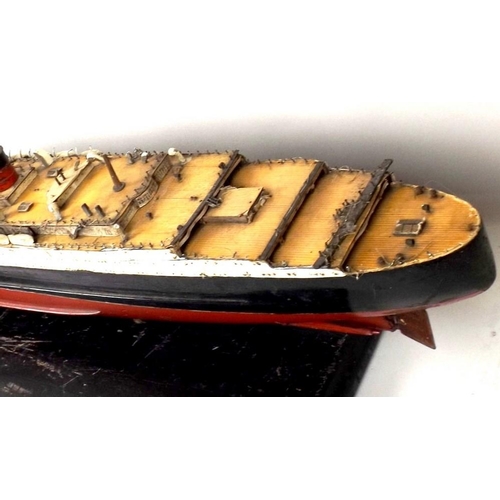 719 - A painted wooden model of the Queen Mary, mid 20th century, with burgundy and black hull, on a woode... 