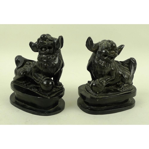 756 - A pair of Chinese carved black hardstone figures of Buddhistic lion dogs, 19th century, carved with ... 