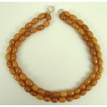 A double stand butterscotch amber bead necklace, early 20th century, thirty four bead string and a t... 