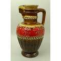 A large West German jug or pitcher with yellow, brown, and red glazes to the exterior, blue glaze to... 