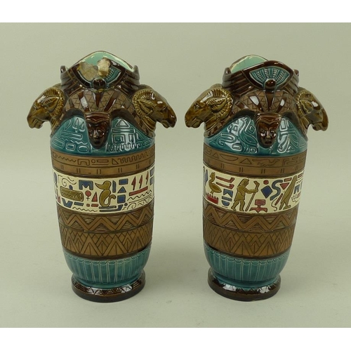 536 - A pair of ceramic Egyptian revival vases with rams head handles, decorated in bands with hieroglyphs... 