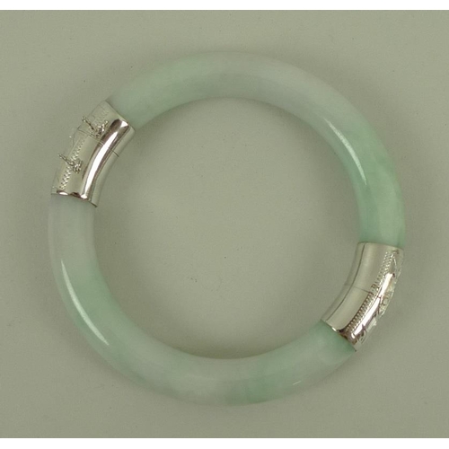 811 - A modern jade bangle, mounted with 14ct white gold engraved hinge and clasp, with safety chain, 6cm ... 