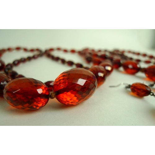 825 - A pair of vintage facet cut amber bead necklaces, circa 1910, of graduated, oval, red treacle colour... 