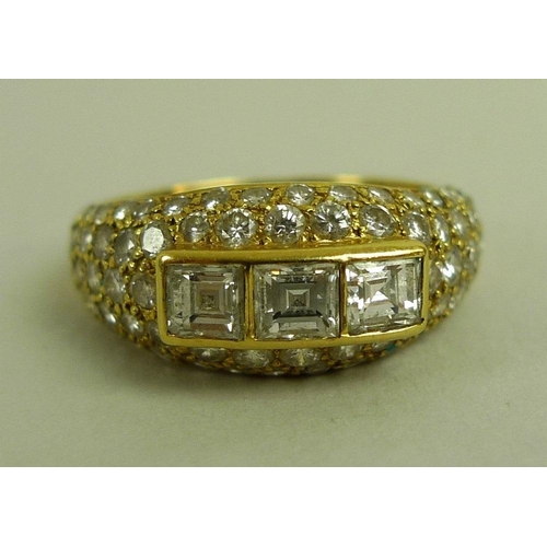 836 - An 18ct gold and diamond modern designed dress ring, of three emerald cut diamonds raised above a di... 