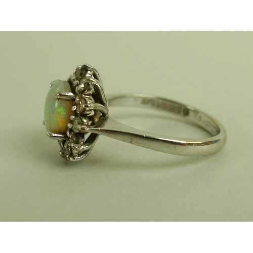 838 - An 18ct white gold and opal dress ring, the central oval cabochon cut opal surrounded by twelve diam... 