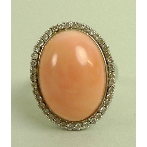 876 - A coral and diamond ring, the oval angel pink cabochon within a surround of brilliant cut diamonds, ... 