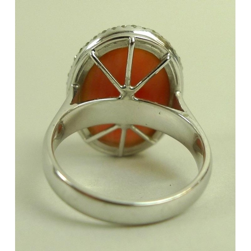 876 - A coral and diamond ring, the oval angel pink cabochon within a surround of brilliant cut diamonds, ... 