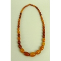 A butterscotch amber necklace of graduated beads, the largest measuring 30mm by 20mm, 90.2g.