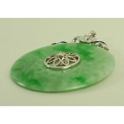 888 - A jade and diamond pendant, the carved jade disc set centrally with floral design and brilliant cut ... 