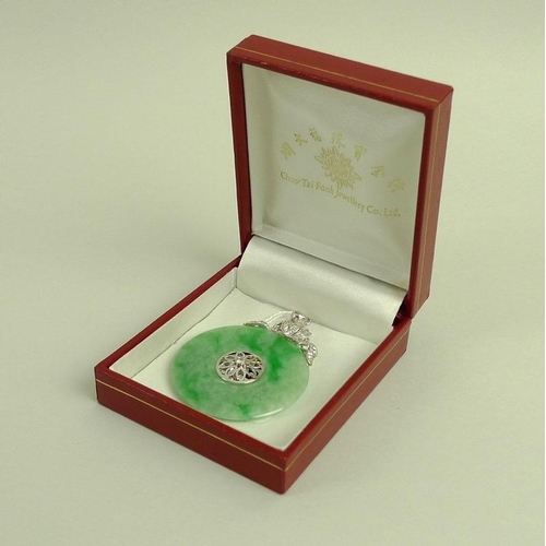 888 - A jade and diamond pendant, the carved jade disc set centrally with floral design and brilliant cut ... 