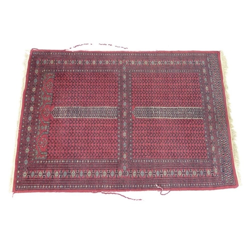 920A - A hand knotted rug, the red ground separated in to four panels decorated with geometric designs and ... 