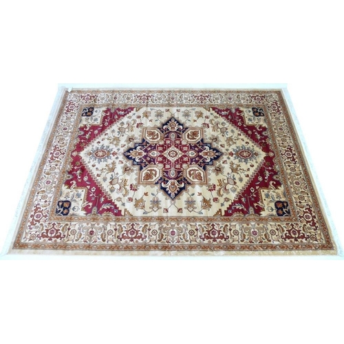 923 - A Heriz rug with beige ground, central lobed medallion, floral field, red and cream corners, wide cr... 