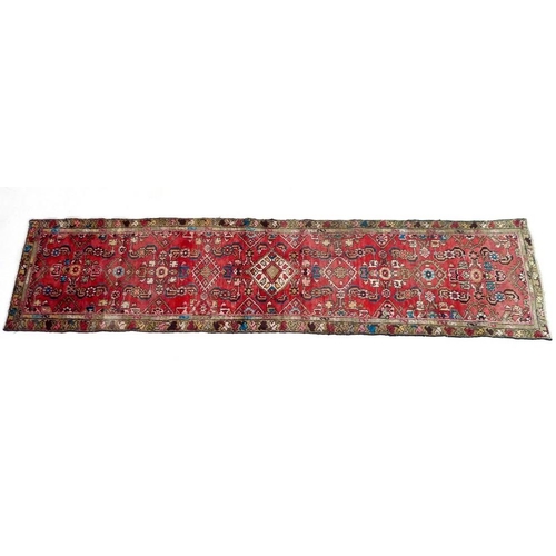 927 - A Hamadan runner with red ground, geometric patterned field with five medallions, multicoloured flor... 