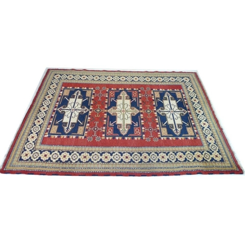 933 - A wool rug with red ground, three rectangular dark blue and cream medallions, multiple cream and pal... 