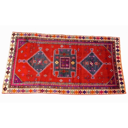 942 - An Azerbaijan rug with red ground and purple detail, three dark blue medallions, multiple borders, 2... 