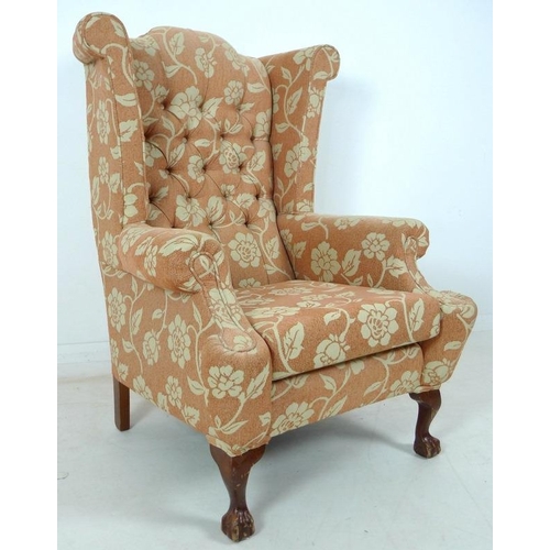 947 - A mid 20th century wing armchair, with carved cabriole legs, upholstered with a salmon coloured butt... 