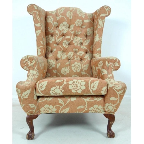 947 - A mid 20th century wing armchair, with carved cabriole legs, upholstered with a salmon coloured butt... 