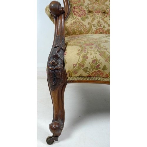 950 - A Victorian nursing chair, the walnut frame carved with roses and scrolls, upholstered in button bac... 