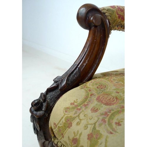 950 - A Victorian nursing chair, the walnut frame carved with roses and scrolls, upholstered in button bac... 