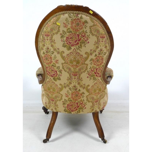 950 - A Victorian nursing chair, the walnut frame carved with roses and scrolls, upholstered in button bac... 