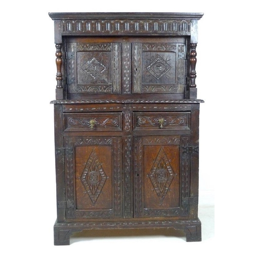 957 - A 17th century narrow court cupboard of conventional form, carved overall with scrolls and geometric... 