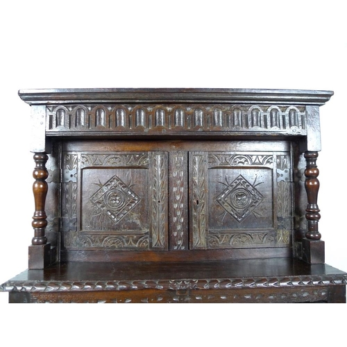 957 - A 17th century narrow court cupboard of conventional form, carved overall with scrolls and geometric... 