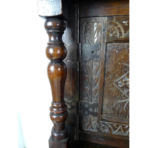 957 - A 17th century narrow court cupboard of conventional form, carved overall with scrolls and geometric... 