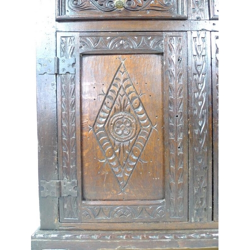 957 - A 17th century narrow court cupboard of conventional form, carved overall with scrolls and geometric... 