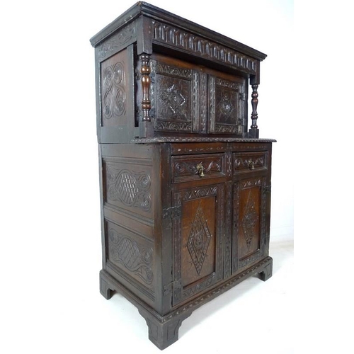 957 - A 17th century narrow court cupboard of conventional form, carved overall with scrolls and geometric... 