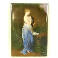 A German painted porcelain plaque of a young woman in Greco-Roman attire holding an amphora, surroun... 