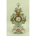 A Dresden china floral mantel clock, decorated in pastel tones with floral relief, gilt highlights, ... 