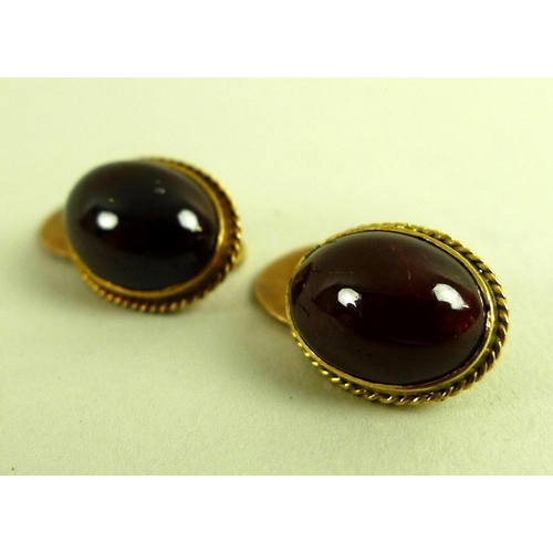 812 - A pair of early 20th century gold cufflinks, set with red hard stone oval cabochons, likely garnet, ... 