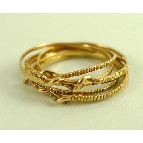 820 - A yellow metal puzzle ring formed of seven rings, two of the bands plain, four ribbed and the centra... 