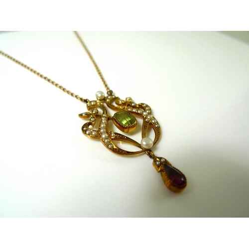 835 - An Art Nouveau 15ct gold, peridot, ruby and seed pearl pendant of scrolled lyre form, in the suffrag... 