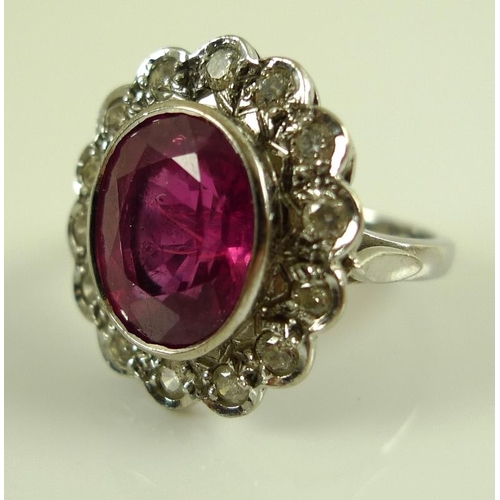 839 - An 18ct white gold, diamond and ruby ring, the central oval cut stone of over 3ct, 12 by 10mm, encir... 