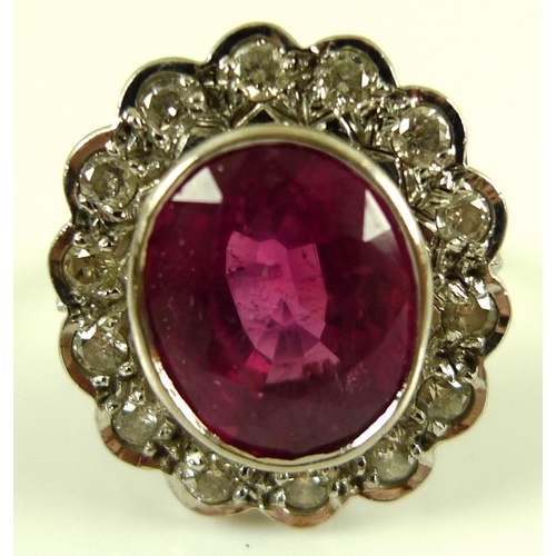 839 - An 18ct white gold, diamond and ruby ring, the central oval cut stone of over 3ct, 12 by 10mm, encir... 